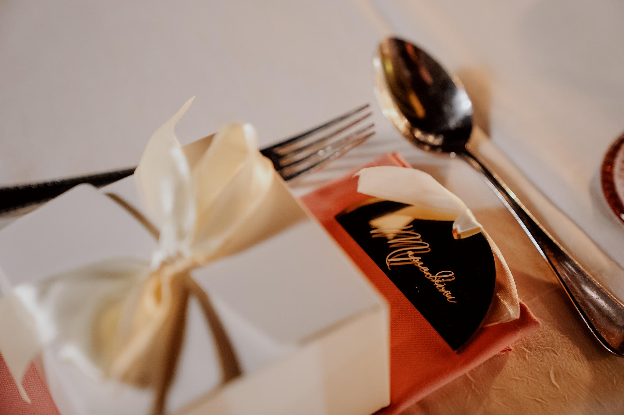 Κοντινή φωτογραφία στα Plexi glass με χαραγμένα τα ονόματα επάνω . Περιέχει η φωτογραφία ένα κουτί λευκό το οποίο είναι η μπομπονιέρα.