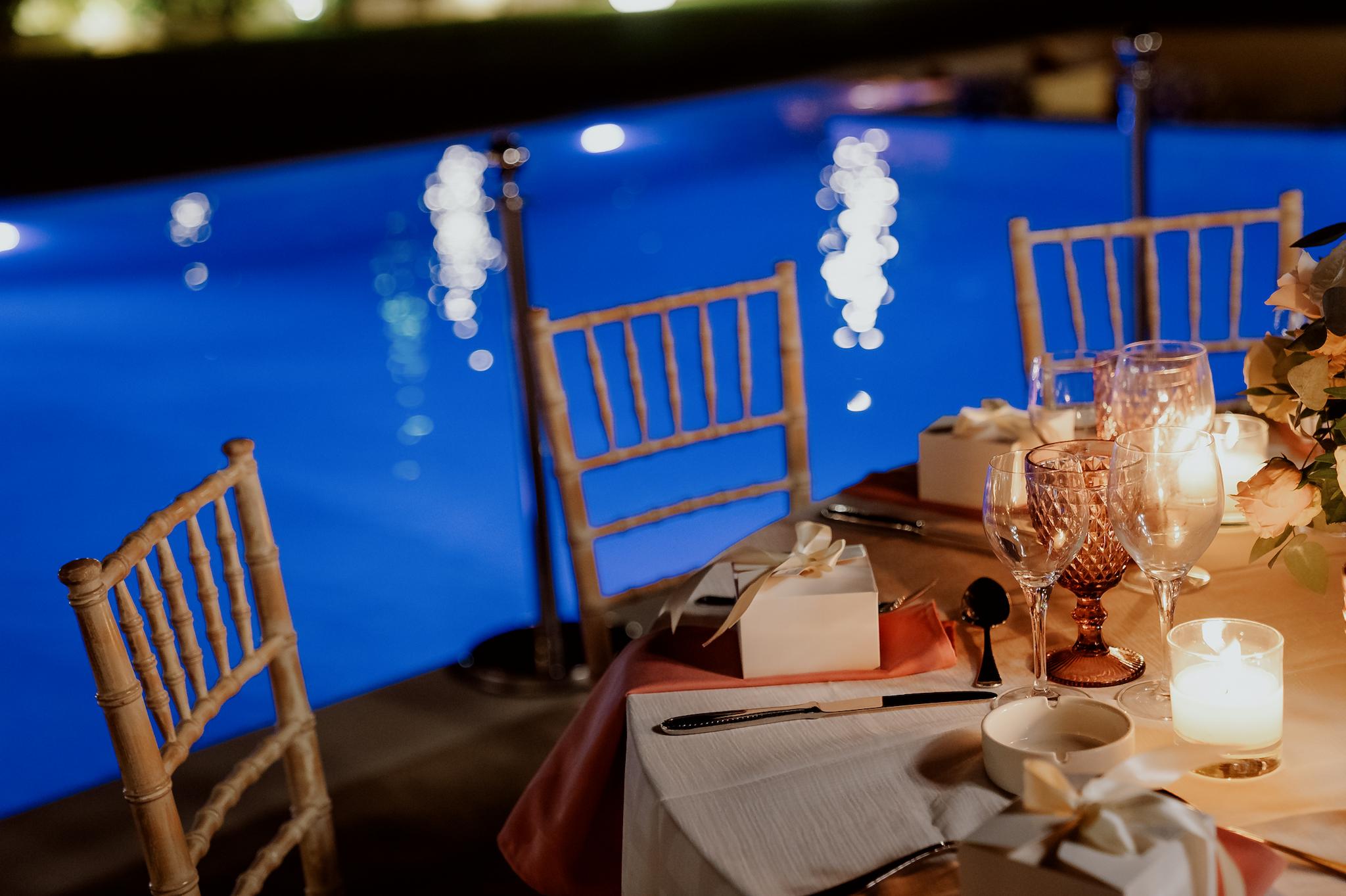 Στολισμός στα τραπέζια με τριαντάφυλλα σάπιο μήλο και λευκά με πολύχρωμα ποτήρια σε ροζ αποχρώσεις και καρέκλες tiffany στο βάθος φαίνεται το πολύχρωμα τοπίο από πράσινο και τα φυτά