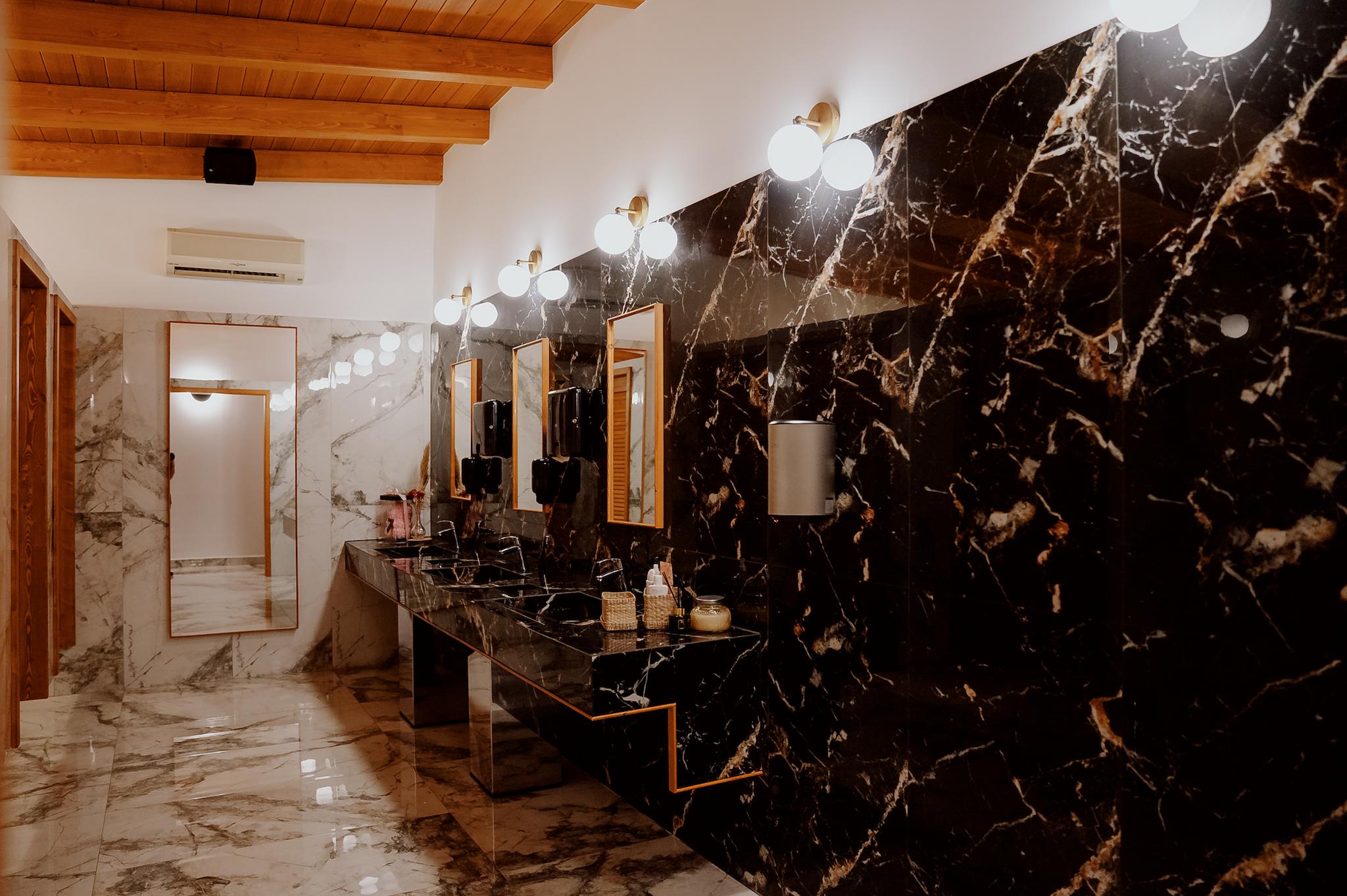 Φωτογραφία από τα μπάνια και τους νιπτήρες που είναι μαύρο μάρμαρο γρανιτοπλακάκι επάνω από κάθε νιπτήρα έχει καθρέπτη