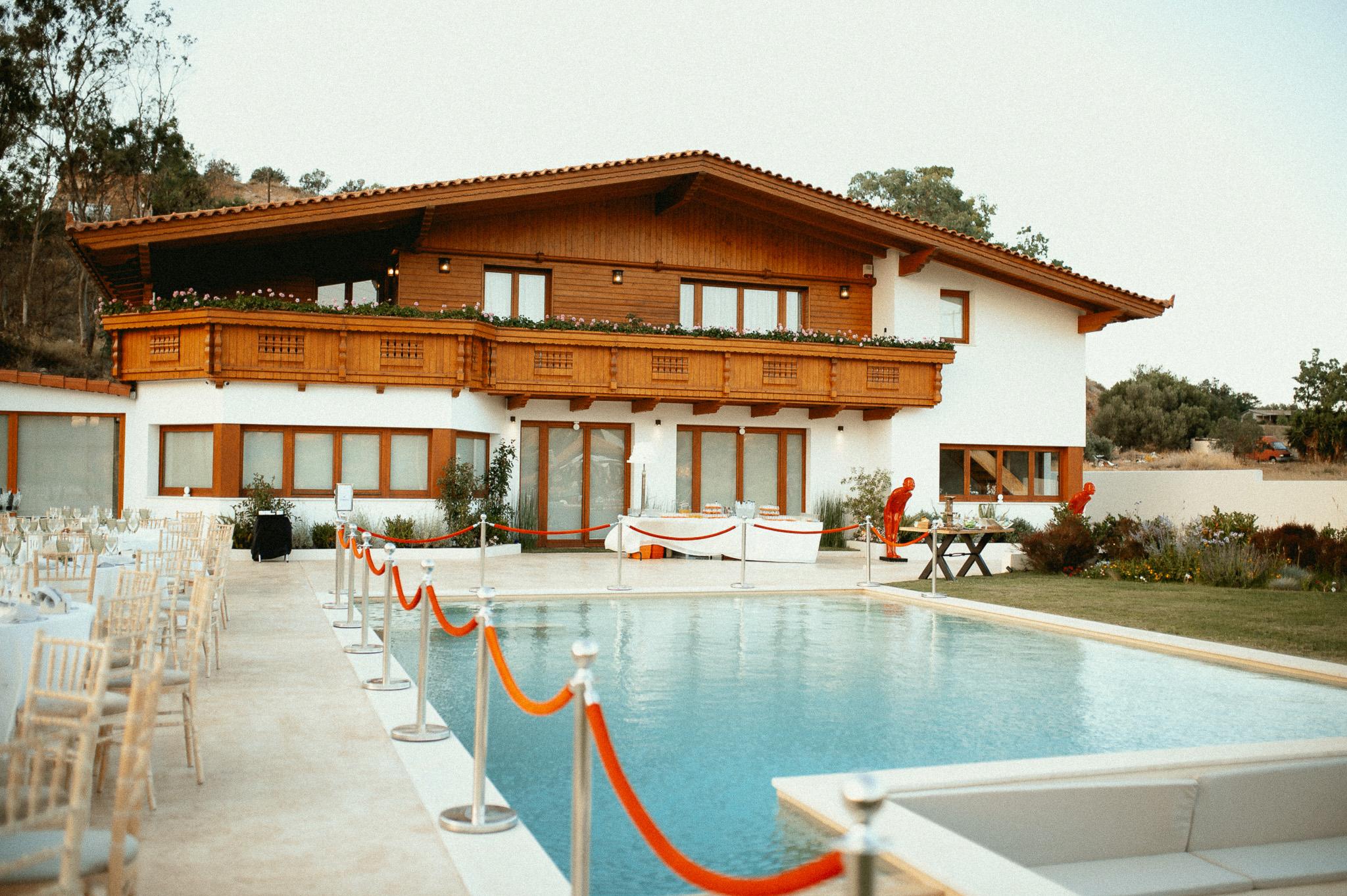 Φωτογραφία που φαίνεται το οίκημα και η πισίνα. Το οίκημα είναι ξύλινο σαν ελβετικό σαλέ με μεγάλες τζαμαρίες μπροστά