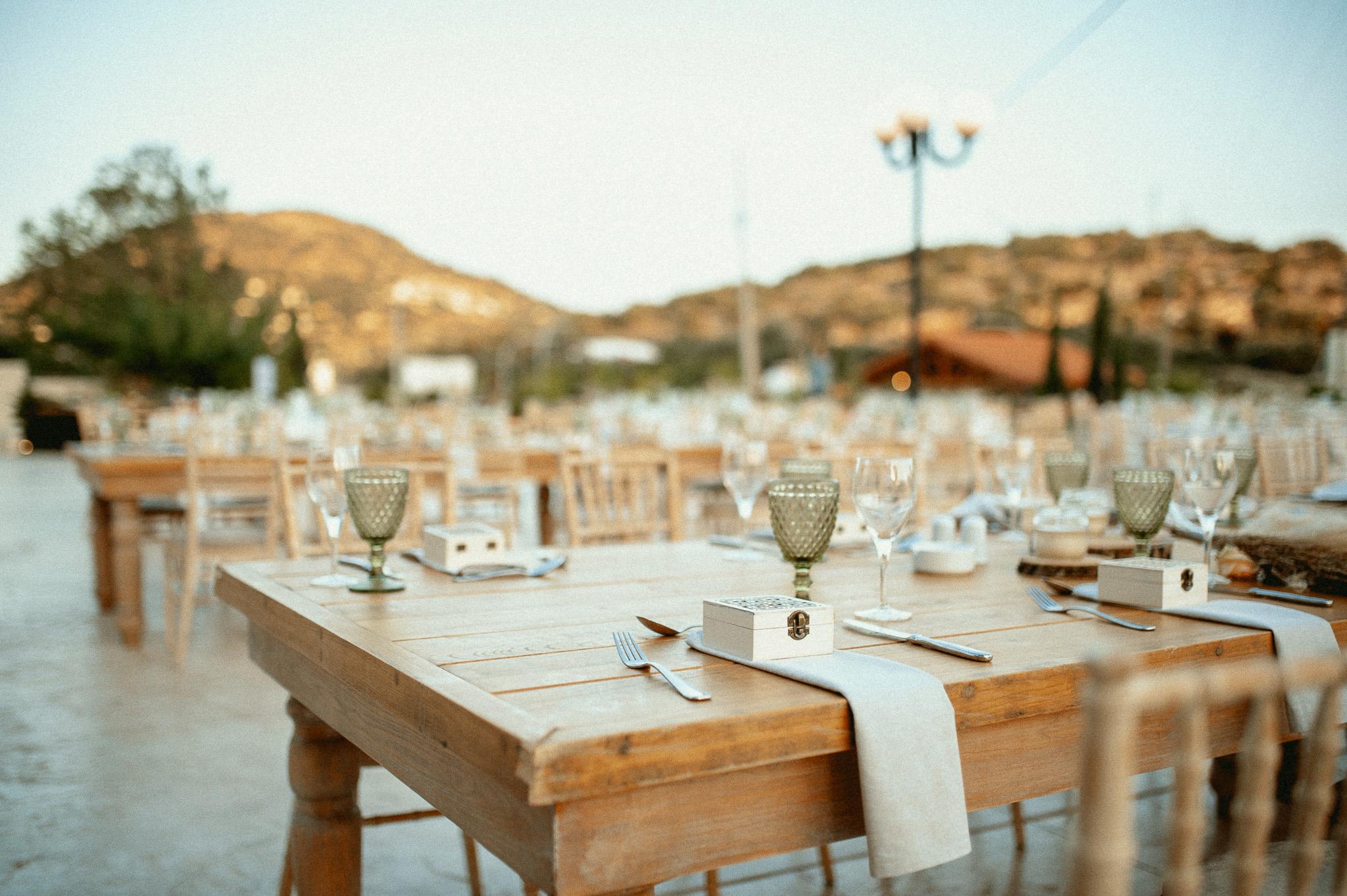 Κοντινή φωτογραφία σε μοναστηριακό τραπέζι με τοποθετημένες καρέκλες ξύλινες tiffany . Τα μοναστηριακά τραπέζια είναι στρωμένα και επάνω έχουν και τον στολισμό ο οποίο είναι ένα βάζο με Pampas σε διάφορα χρώματα