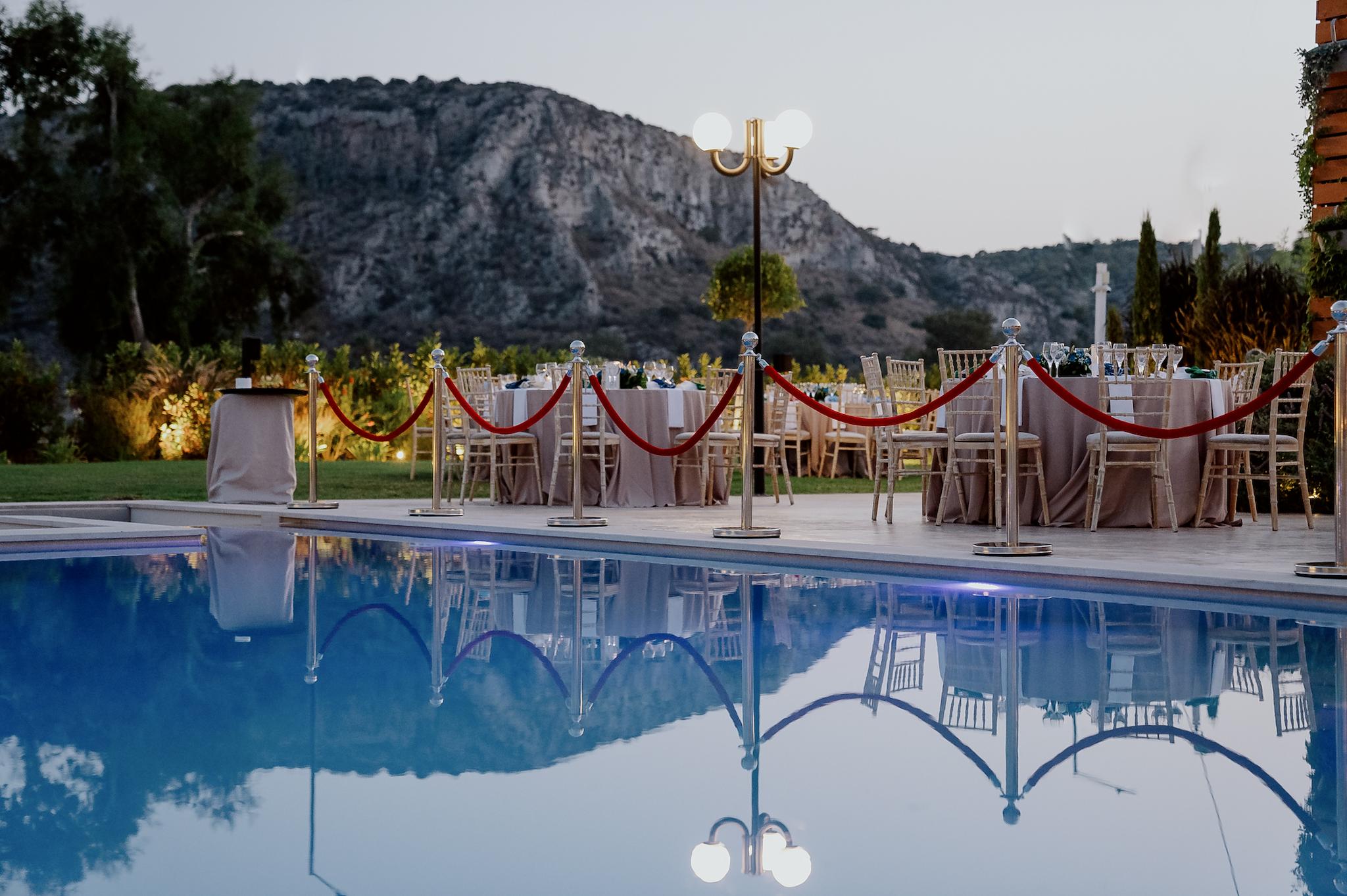 νερό από την πισίνα του κτήματος με φόντο τα τραπέζια που έχει στήσει το catering και περιμετρικά έχει καρέκλες tiffany