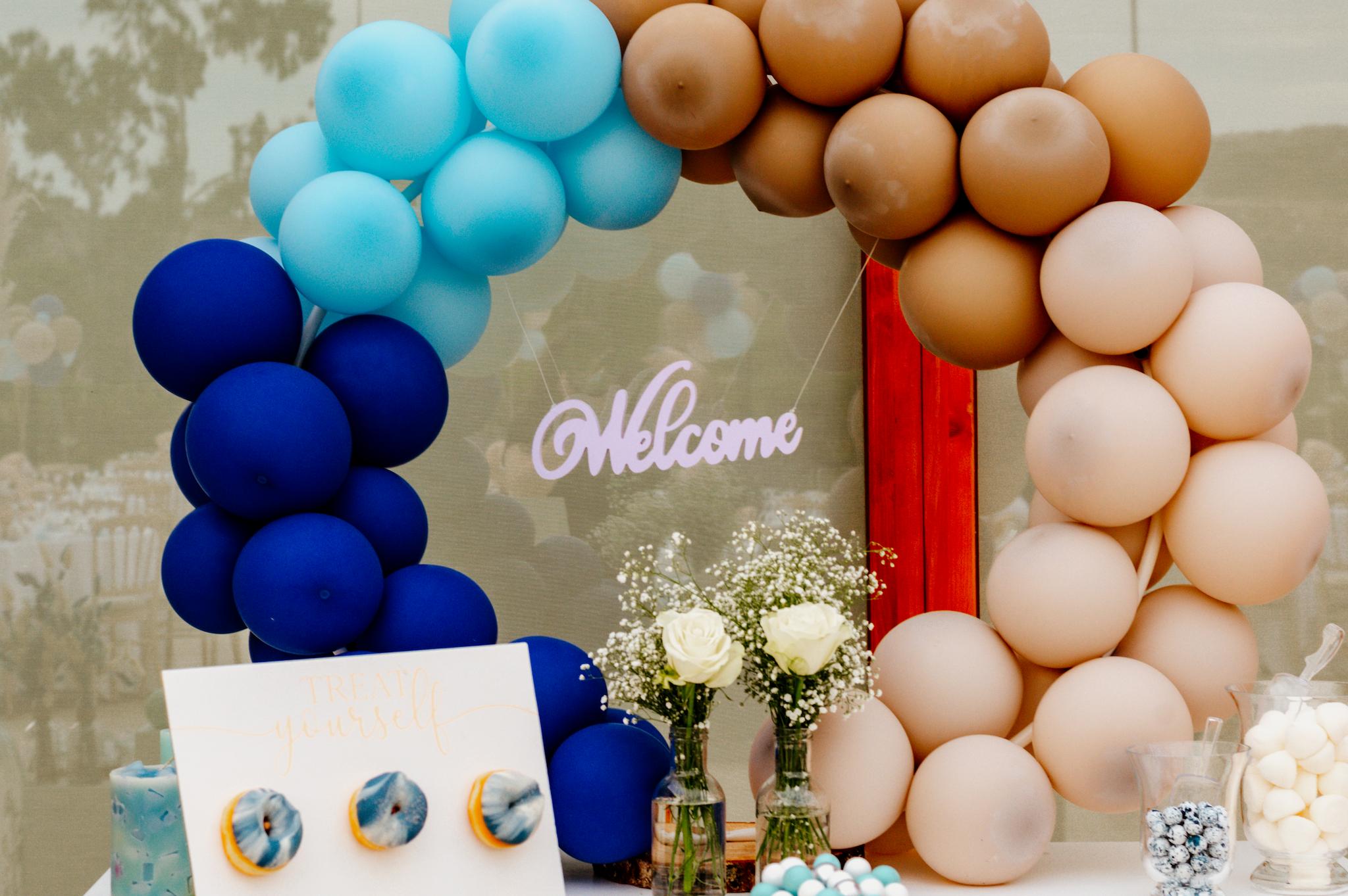 Φωτογραφία είναι τραβηγμένη από πάνω η οποία έχει τραβηγμένα γλυκά τα οποία είναι στο candy bar. Δείχνει την τούρτα και κάποια cake pops όπως επίσης και τα donut και τα macarons