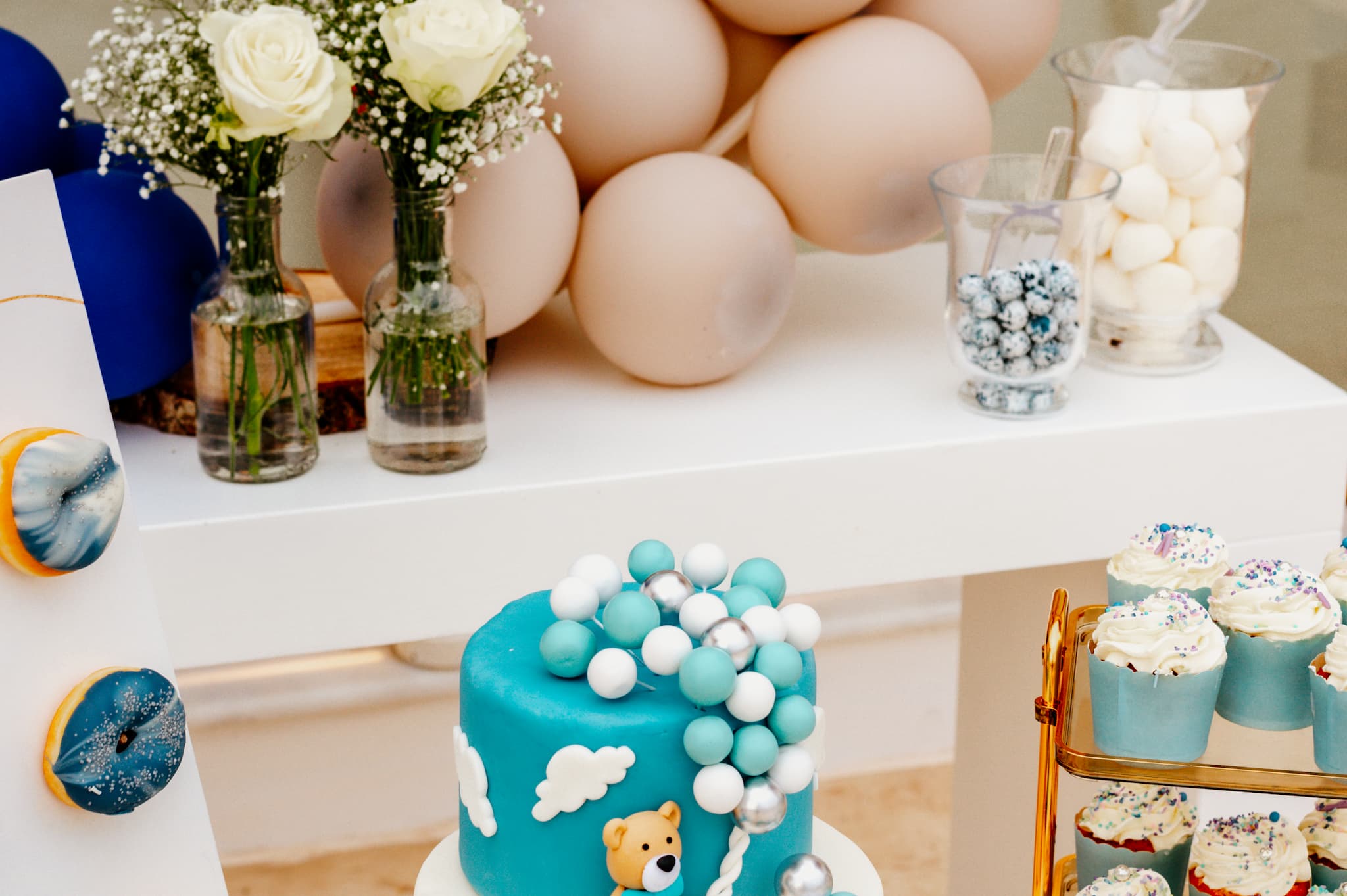 Φωτογραφία είναι τραβηγμένη από πάνω η οποία έχει τραβηγμένα γλυκά τα οποία είναι στο candy bar. Δείχνει την τούρτα και κάποια cake pops όπως επίσης και τα donut και τα macarons