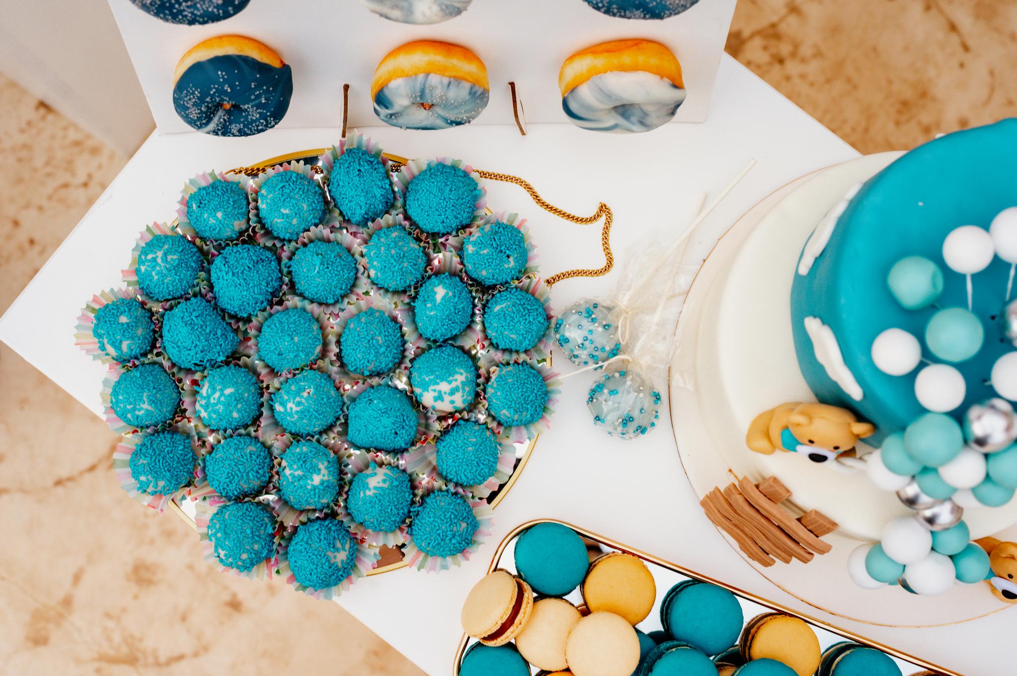 Φωτογραφία είναι τραβηγμένη από πάνω η οποία έχει τραβηγμένα γλυκά τα οποία είναι στο candy bar. Δείχνει την τούρτα και κάποια cake pops όπως επίσης και τα donut και τα macarons