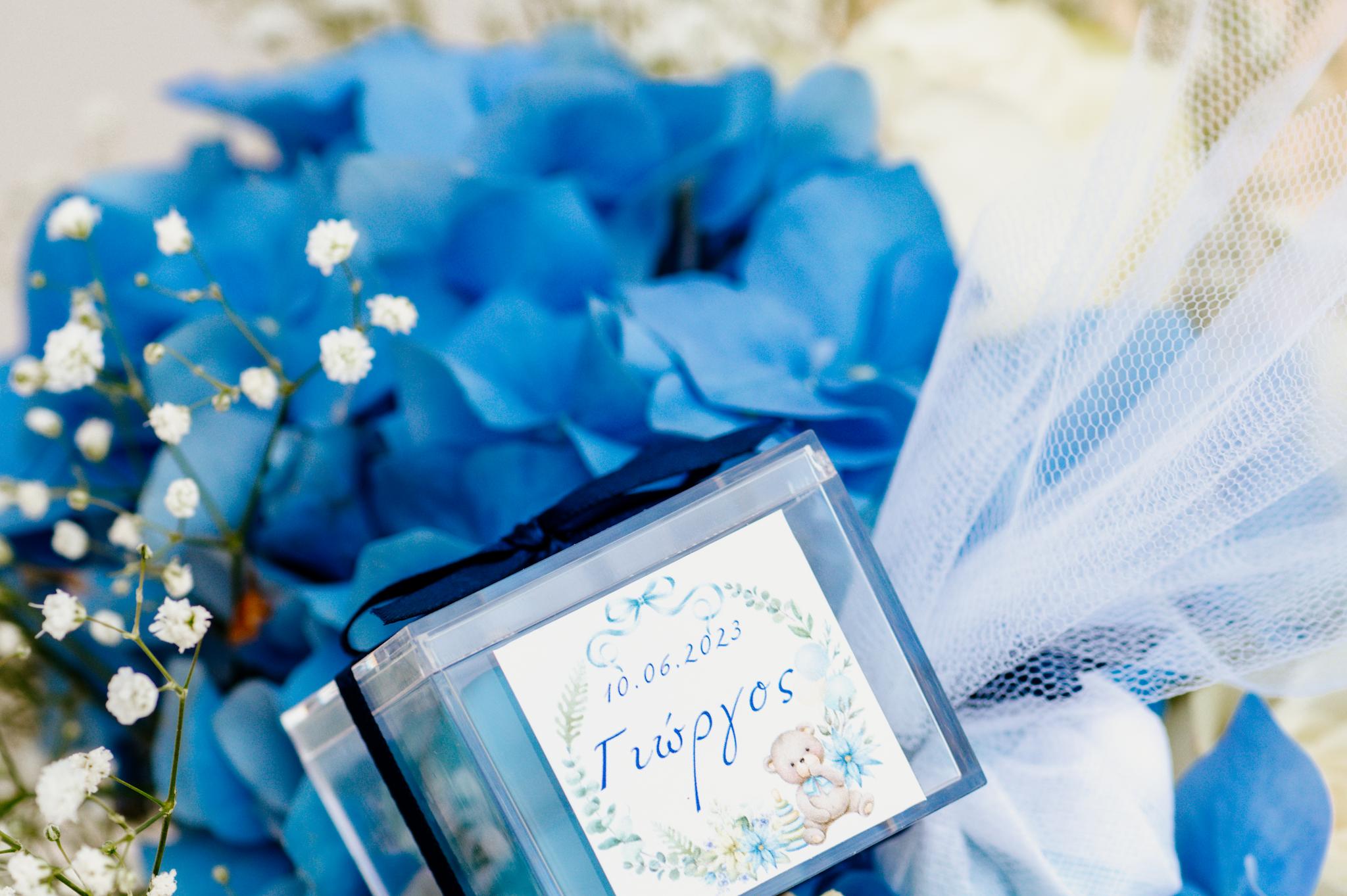 Κοντινή φωτογραφία μπομπονιέρας. Η μπομπονιέρα είναι ένα μπλε σκούρο κεράκι με το όνομα του παιδιού